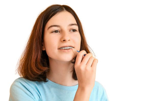 A girl brushing teeth with braces.