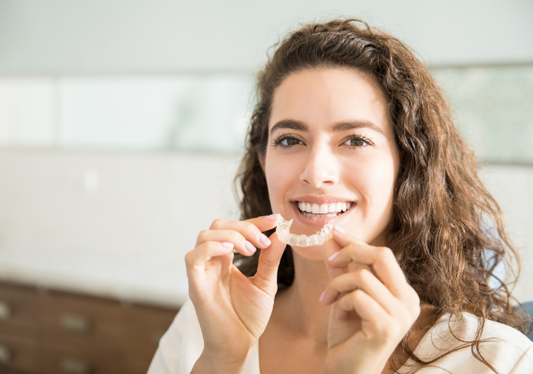 A girl applying clear retainers.