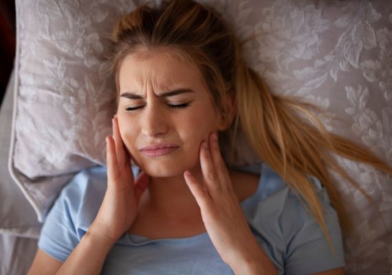 A woman holding her jaw due to night guard pain 