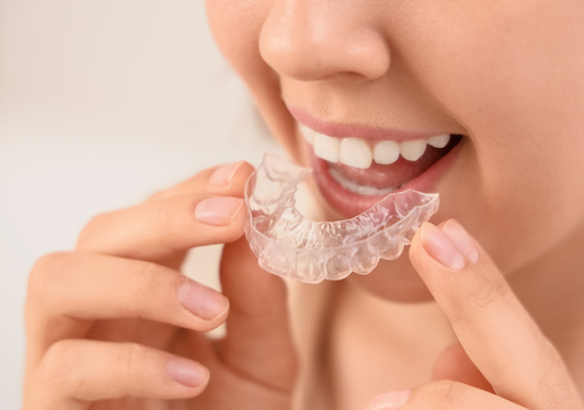 Woman putting invisible aligners in her mouth 
