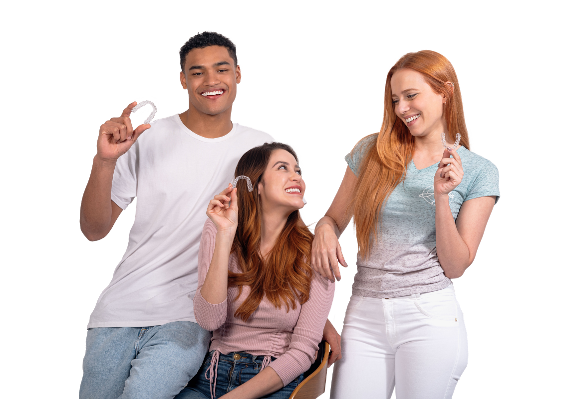 Three smiling people holding clear aligners.