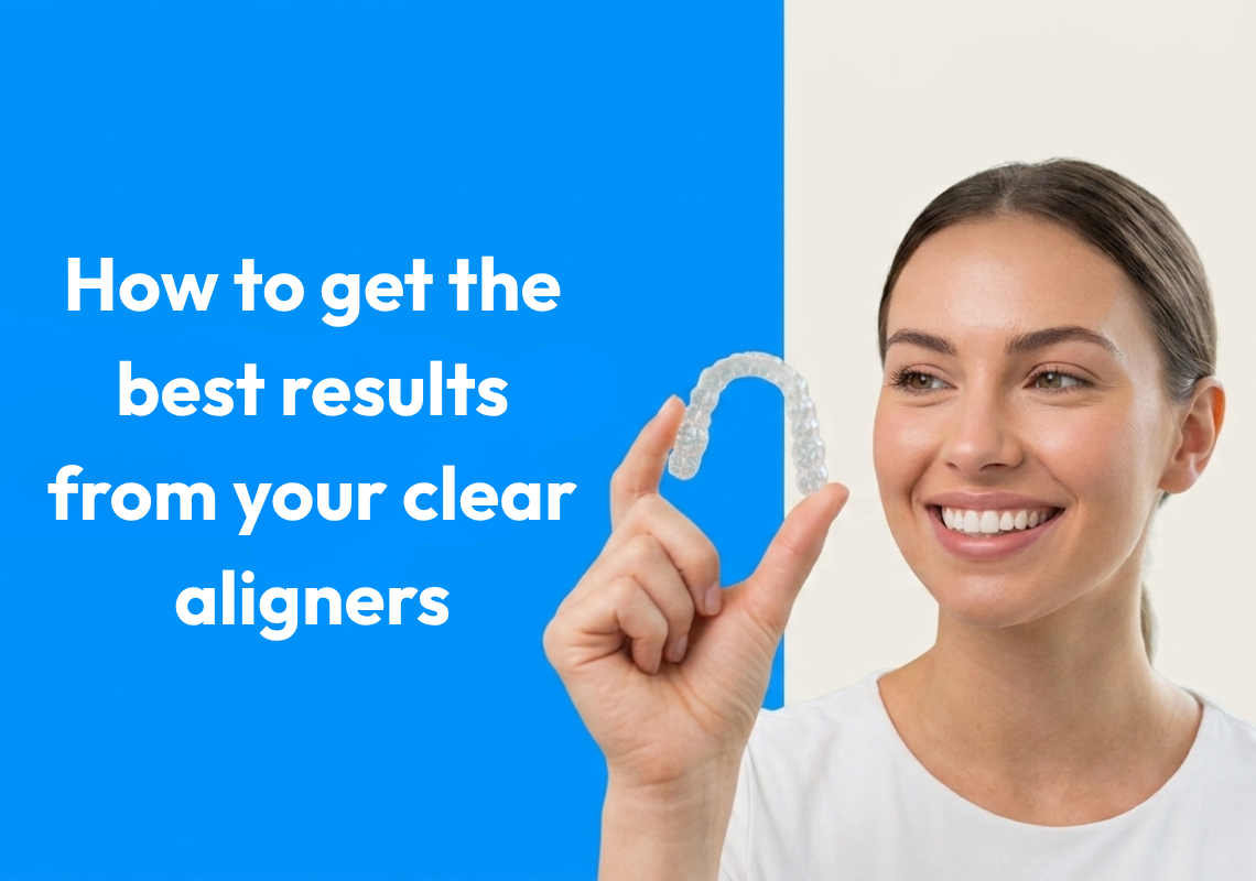  A smiling woman holding a clear aligner tray and looking at it. 